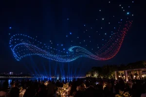 Synchronized drone light show creating an abstract wave above a waterfront event
